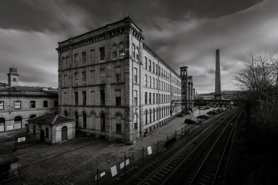 A disused Victorian stone mill beside a railway line, awaiting redevelopment
